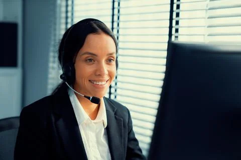 Competent female operator working on computer and while talking with clients. Foto stock