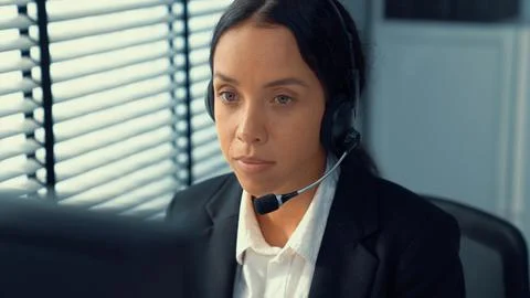 Competent female operator working on computer and while talking with clients. Foto stock