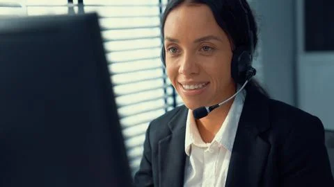 Competent female operator working on computer and while talking with clients. Foto stock