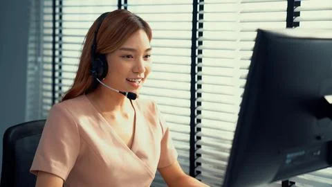 Competent female operator working on computer and while talking with clients. Foto stock