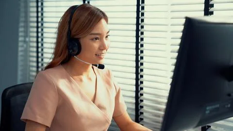 Competent female operator working on computer and while talking with clients. Foto stock