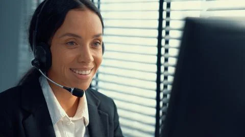 Competent female operator working on computer and while talking with clients. Foto stock