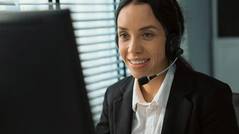 Competent female operator working on computer and while talking with clients. Foto stock
