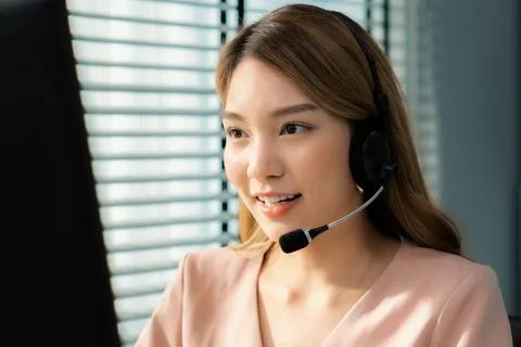 Competent female operator working on computer and while talking with clients. Foto stock