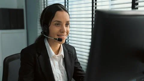 Competent female operator working on computer and while talking with clients. Foto stock