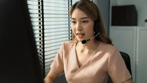 Competent female operator working on computer and while talking with clients. Foto stock