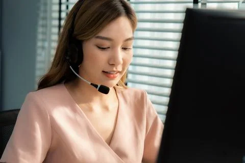 Competent female operator working on computer and while talking with clients. Foto stock