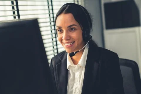 Competent female operator working on computer and while talking with clients. Stock Photos