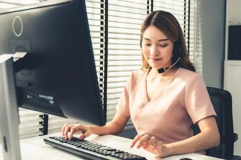 Competent female operator working on computer and while talking with clients. Stock Photos