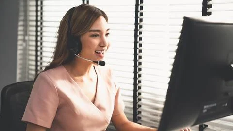 Competent female operator working on computer and while talking with clients. Stock Photos