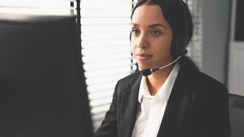 Competent female operator working on computer and while talking with clients. Foto stock