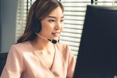 Competent female operator working on computer and while talking with clients. Foto stock