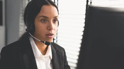 Competent female operator working on computer and while talking with clients. Foto stock