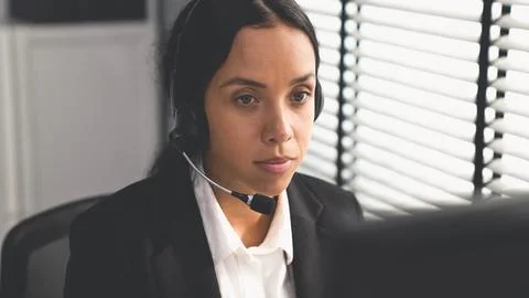 Competent female operator working on computer and while talking with clients. Foto stock