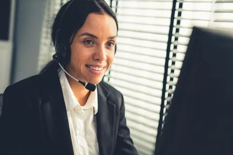 Competent female operator working on computer and while talking with clients. Foto stock