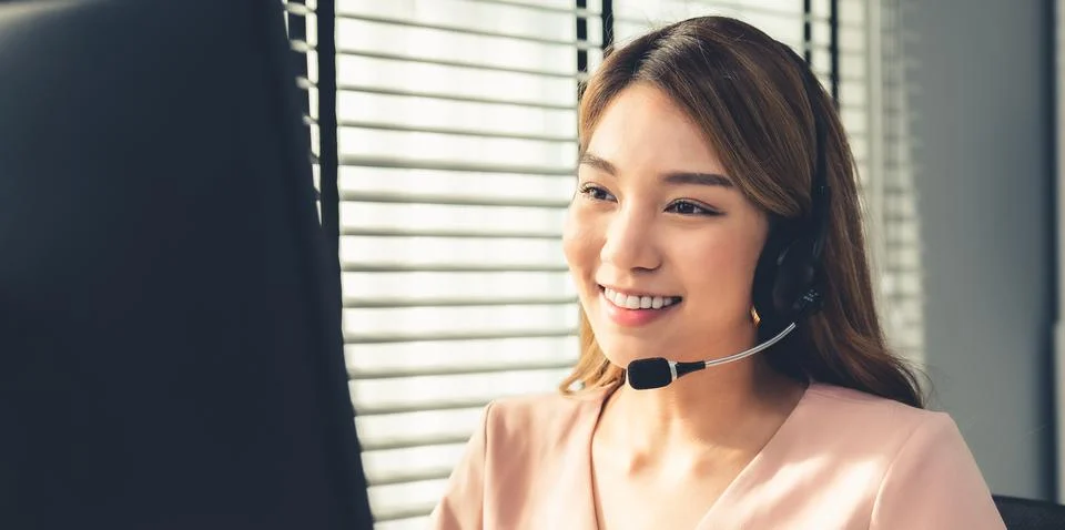 Competent female operator working on computer and while talking with clients. Foto stock