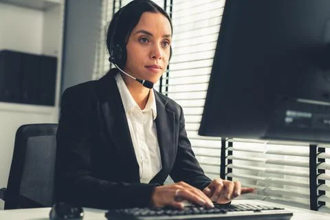 Competent female operator working on computer and while talking with clients. Foto stock