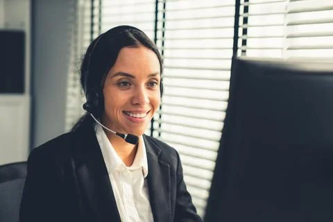 Competent female operator working on computer and while talking with clients. Foto stock