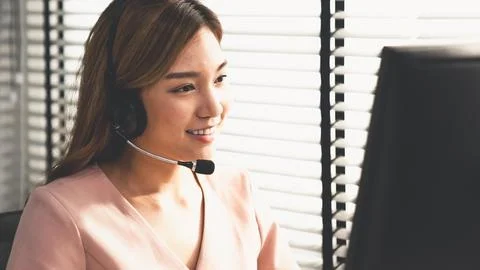 Competent female operator working on computer and while talking with clients. Foto stock