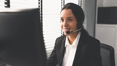 Competent female operator working on computer and while talking with clients. Foto stock