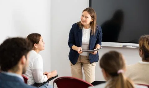 Competent female tutor teaching students in college classroom Stock Photos