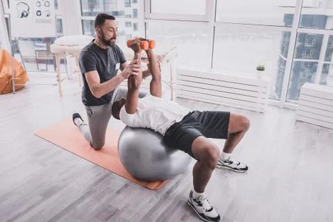 Competent young trainer supporting his injured client Stock Photos