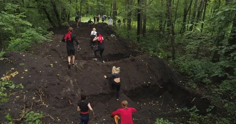 Competitors jump over a big ditch. Obstacle course. Aerial view, 4K. Stock Footage 124042101