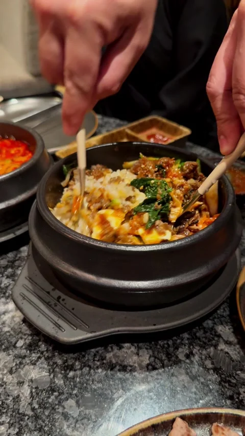 Compilation of Korean BBQ dining experience showing pouring sauce on bibimbap, Stock Footage 337462157
