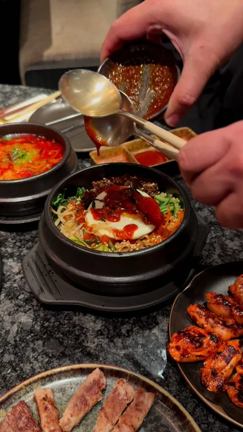Compilation of Korean BBQ dining experience showing pouring sauce on bibimbap, Stock Footage 337462160