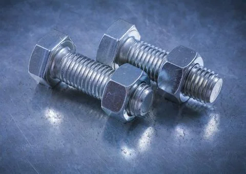Compilation of threaded bolts and construction nuts on a metallic background Stock Photos