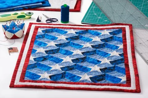 Completed quilt with stylized elements of American flag, patchwork tools Stock-Fotos