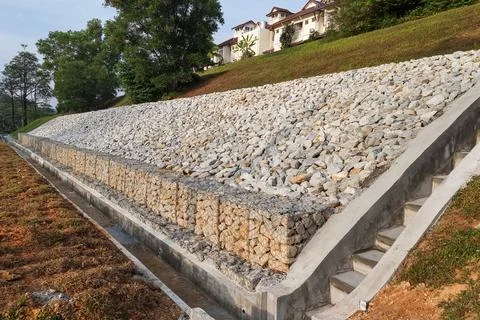 Completed slope retention construction design with rocks and mesh to manage Stock Photos