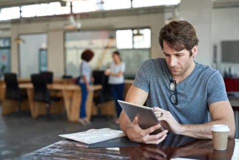 Completely focused on his task. Shot of a young man working on a digital tablet Stock Photos