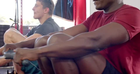 Completing final rowing stroke, diverse men on rowers in crossfit gym Stock Footage 338325458