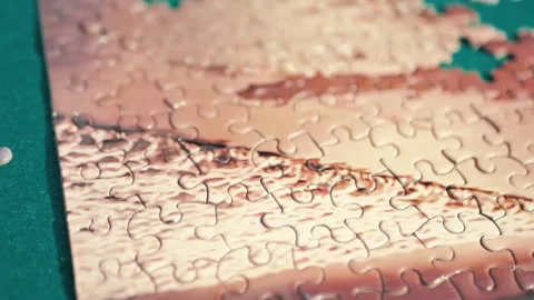 Completing the puzzle. Close up on a woman's hand putting a piece of puzzle Stock Footage 223385888
