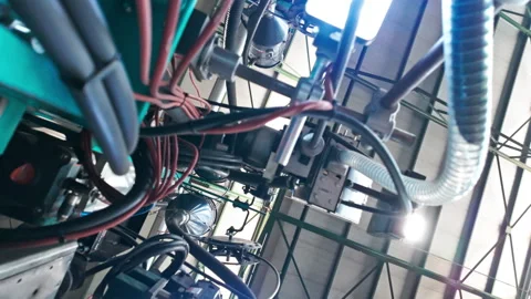Complex machinery with cables, pipes, and industrial equipment in a factory Stock Footage 296366405