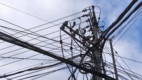 Complex network of power lines and utility pole against cloudy blue sky Stockfoto's