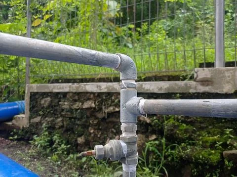 Complex outdoor plumbing installation featuring galvanized steel pipes, fit.. Stock Photos