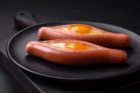 Composite concept of fried eggs inside a cut sausage with spices Stock Photos