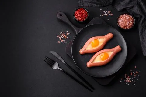 Composite concept of fried eggs inside a cut sausage with spices Stock Photos