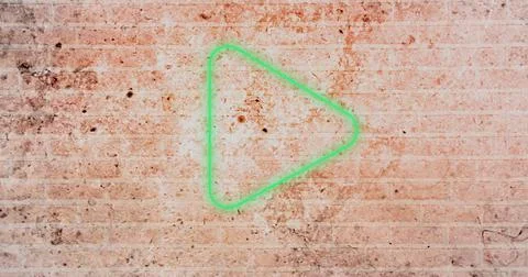 Composite of digital green play button icon against dirty brick wall, copy space Stock Photos