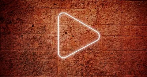 Composite of illuminated white play button icon against grunge wall, copy space Stock Photos