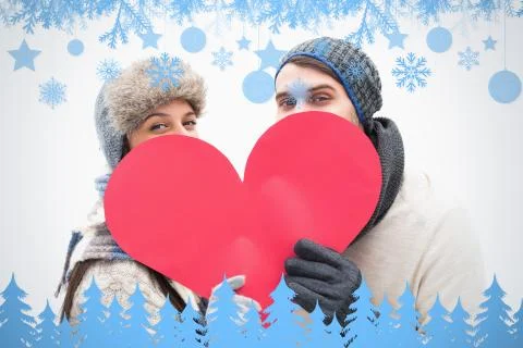 Composite image of attractive young couple in warm clothes holding red heart Illustrazione stock