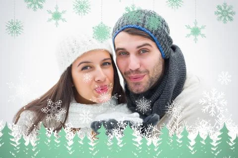 Composite image of attractive young couple in warm clothes blowing Illustrazione stock