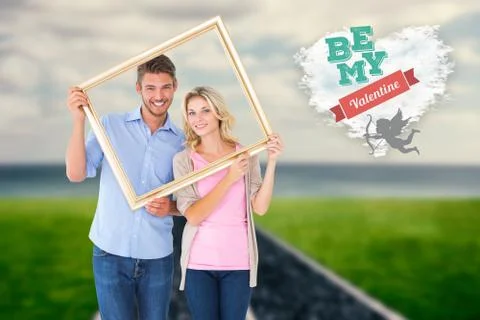 Composite image of attractive young couple holding picture frame Ilustração Stock