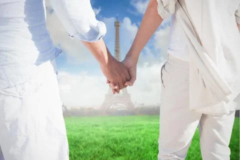 Composite image of couple on the beach looking out to sea holding hands Fotos Stock