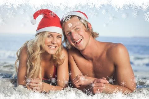 Composite image of couple lying on beach wearing christmas hats Ilustração Stock