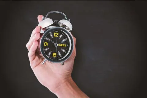 Composite image of cropped hand of man holding alarm clock Foto stock