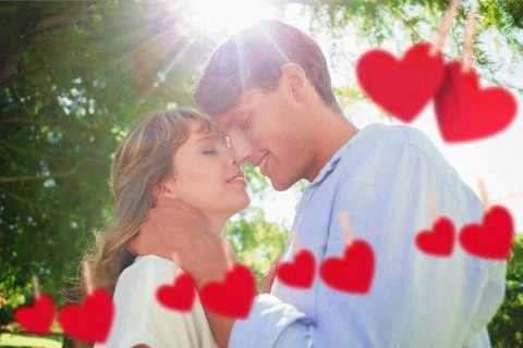 Composite image of cute couple hugging and smiling in the park Ilustración de archivo