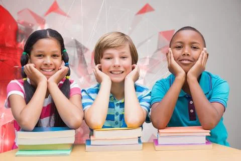 Composite image of cute pupils looking at camera in library Foto stock